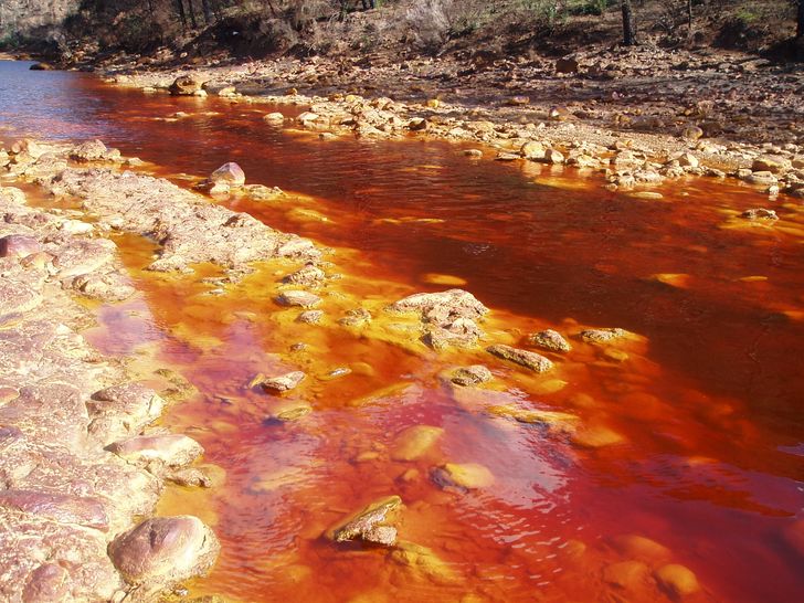 The Rio Tinto river in Spain flows red and orange due to its extreme acidity and high levels of iron and heavy metals.