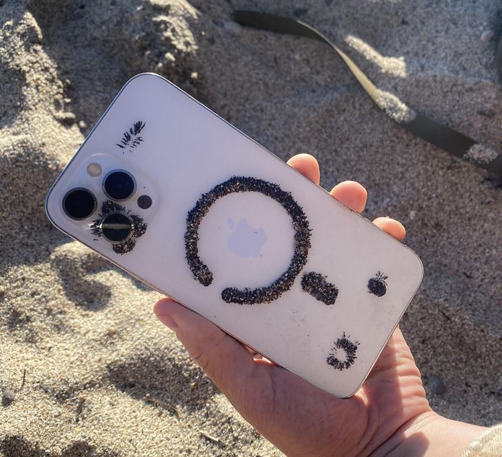 The phone has magnets, so the iron in the sand got stuck to it.