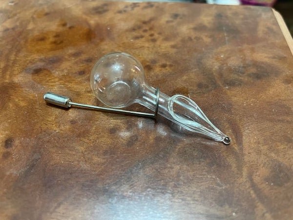 Small glass bulb attached to open tube (not a pipe) with wire hanger(maybe?) found in vintage jewelry box – no markings, words, or numbers

A: Lapel Pin Vase