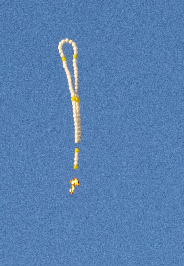 What is this weird chain of balloons I spotted slowly sinking in the sky?

A: Looks like a rosary made of balloons.
Probably for some religious holiday.