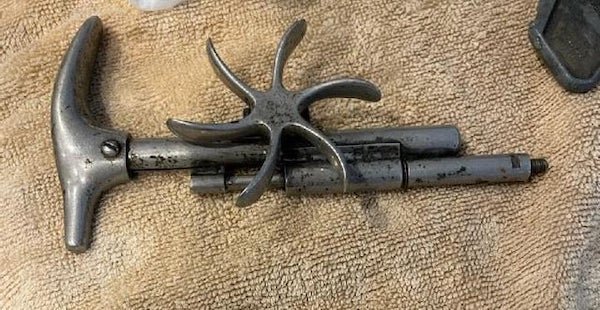 Metal object with handle like a cane, and some type of thumb wheel. About 10″ long and weighs about a pound.

A: It’s a Trephine. It’s used to make holes in the skull to relieve pressure.