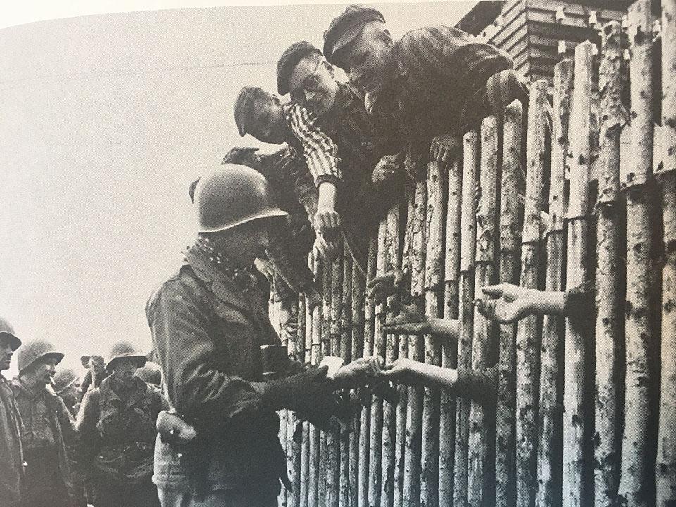 An American soldier gives cigarettes to a few of the more than 30,000 liberated concentration camp inmates at Dachau on April 29, 1945. GIs had a hard time believing Germans who protested they did not know about the camps. Dachau was just ten miles from Munich