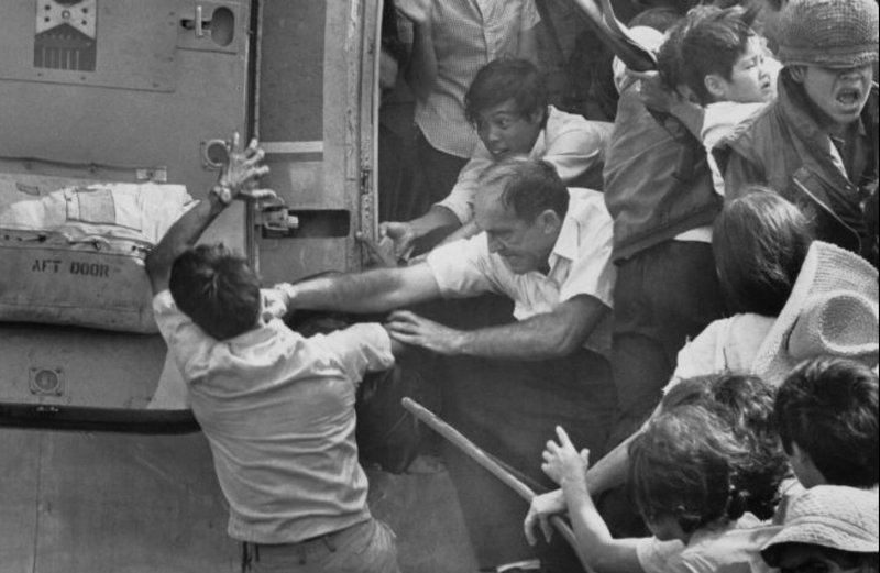 An American man punching a Vietnamese man trying to board one of the last helicopters to leave Saigon.