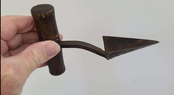 Small, triangular metal shovel/scoop attached perpendicularly to a wooden handle.

A: I believe that is for opening and/or reaming a hole in a barrel (like a wine barrel).