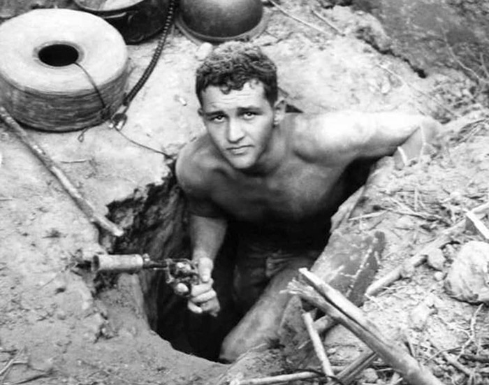 A tunnel rat about to enter a Việt Cộng tunnel with a suppressed revolver, Vietnam, 1960s.⁣