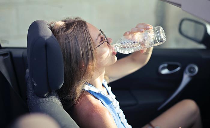 woman drinking water out of plastic water bottle