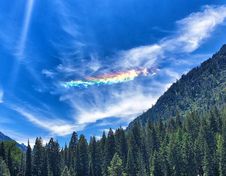 A fiery feather of a rainbow in the clouds over Wallowa Lake in Oregon