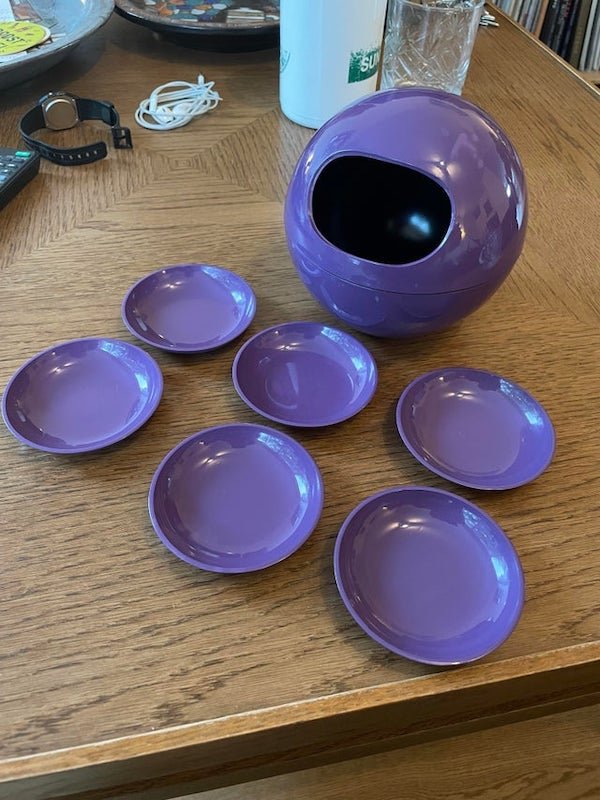 Plastic purple bowl/container with detachable halves containing six small plates, that don’t fit in the hole. Also the hole is so small you can’t really pick anything from it (like nuts or olives)

A: It is for nuts. There would have been a matching serving spoon that is now missing.