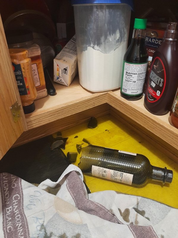 Brand new bottle of olive oil fell off the bottom shelf.