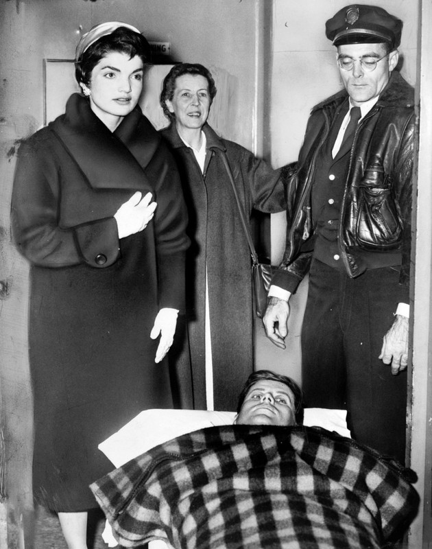 John F. Kennedy leaving on a gurney from hospital following spinal surgery, as his wife Jacqueline stands over him. December 1954