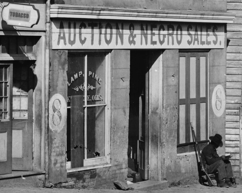 George N. Barnard’s 1864 photograph of a slave trader’s business on Whitehall Street, Atlanta, Georgia, shows a United States Colored Troop Infantryman [Corporal] just by the door