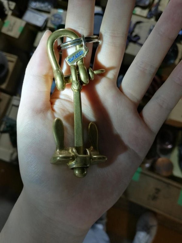Metal (copper?) key chain from Japan with oddly shaped parts that either rotate or slide. The little tag says ‘Huis Ten Bosch’ which according to google is a Dutch theme park in Japan.

A: It’s a novelty anchor, in miniature.