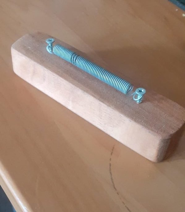 Wooden block with 2 screws and a spring in between

A: It’s a card holder