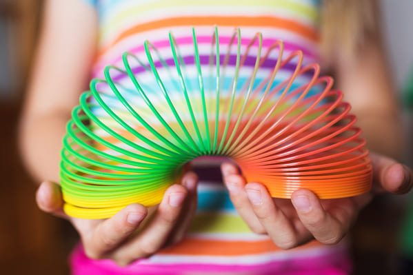 “Slinky, the toy. It was originally designed during WW2 to help sensitive instruments remain steady on ships… to counter the effects of pitch, roll, and yaw. The engineer working on them knocked one off his desk accidentally, saw the way it moved from the table to the chair, to the floor, and a new purpose was born.

On a side note… during the Vietnam War, when the Slinkys were metal, radio operators would carry them through the deep jungles. If they couldn’t get a good signal in the jungle mountains, they’d sling a Slinky high into the tree limbs while holding onto one end. It created an instant antenna extension that they would attach to the radio.”