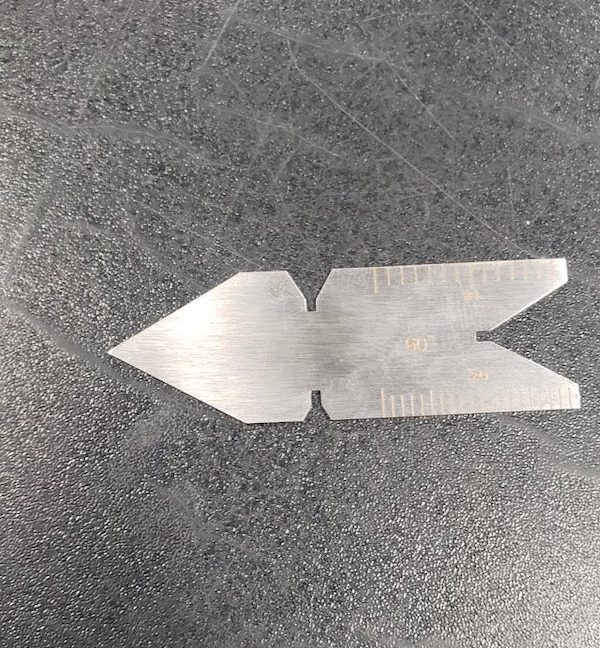 This was found at my work (marina) made of stainless steel, the other side has a scale of 24 and 32. Is it some kind of print alignment tool?? Google image had nothing.

A: It is a grinding and centre setting gauge for tooling