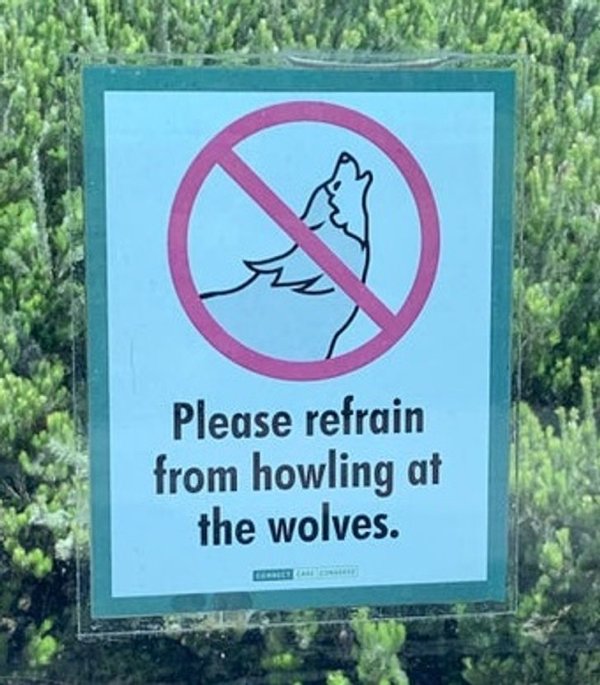 street sign - Please refrain from howling at the wolves.