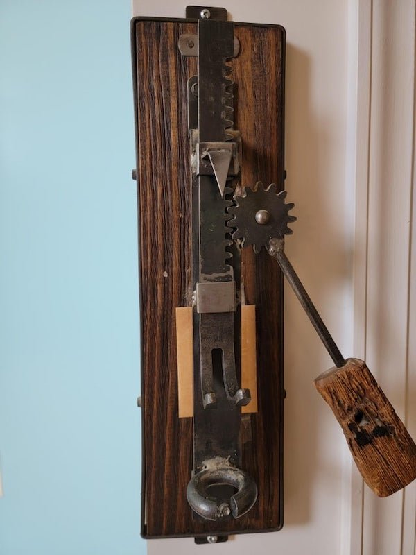 What is this antique crank press/device on the wall of my friend’s house? The plate reads “SENGER 1952”.

A: It’s a corkscrew puller. There is a piece missing, the actual corkscrew. You put the corkscrew into the bottle’s cork, and this easily pulls it out.