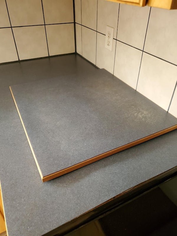 What is this ‘extra’ square of countertop? It’s covered in the same laminate as the counter but has rubber feet on the bottom. I was thinking you could put it on the stove for extra counter space but it’s not really the same size.

A: It’s a cutting board. Common for scrap countertop to be made into matching cutting board for home owner.