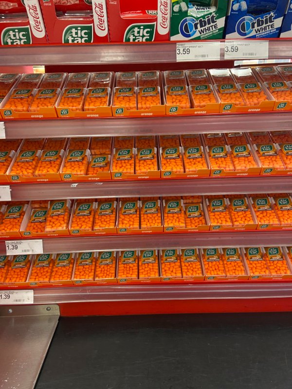 This amount of orange tic-tacs being sold at this checkout aisle.