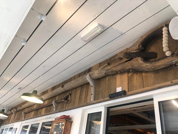 What is this wooden pole, with a beaded rope at the end? At a seaside cafe in Wales, with boating/sea memorabilia covering the walls. Long (approx 10m) wooden pole, with a u-shaped curve at the end. It also has a handle next to the curve and a rope ‘closing’ it with beads.

A: It’s an old-fashioned boom.