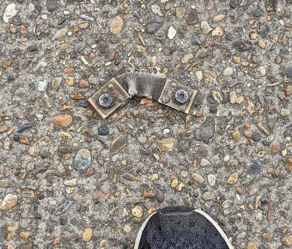 Saw it on the pavement (sidewalk) in London. It looks like a piece of fabric between two bolts stuck to the pavement.

A: It was holding down tubes for a pneumatic traffic counter.