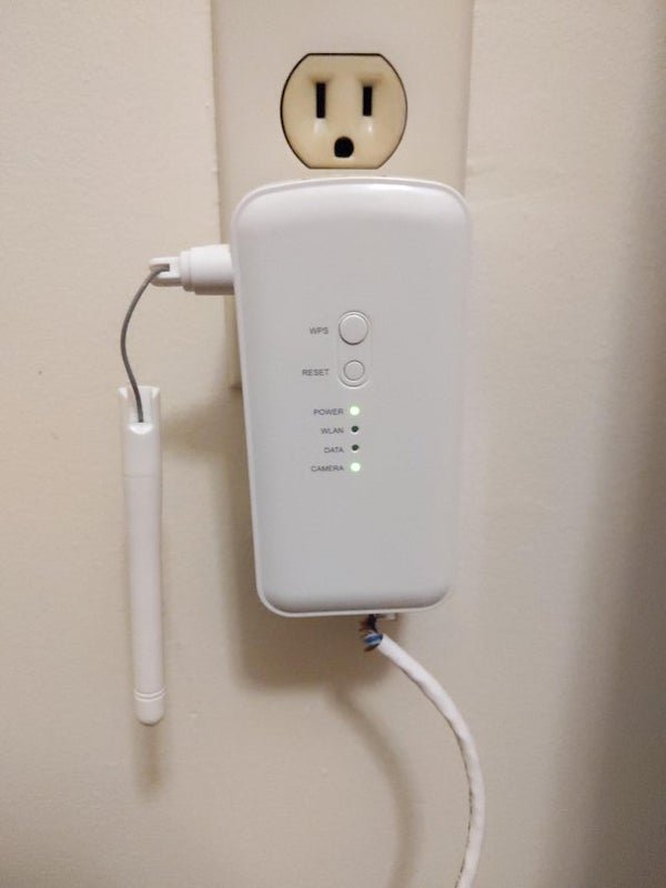 I think this is part of a wireless security camera, but I’m a little freaked out that it’s plugged in in the bedroom of an AirBnB in which I’m currently staying. Do I have anything to worry about? The wire goes into the wall and disappears.

A: This is a wireless bridge for a Vivint security camera. The camera is likely located outside. It is very quite noticeable and would not be able to be hidden inside. It has definitely seen better days. The lack of activity on the wlan and data lights leads me to believe the system may be defunct and the camera offline. Someone may have held down the reset button for 10seconds triggering a factory reset.