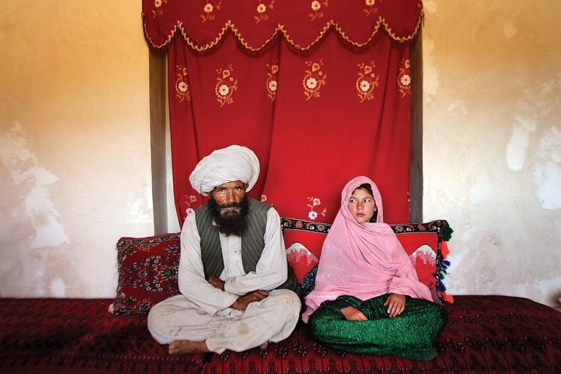 An 11-year-old girl in Afghanistan, sits beside her fiancé, estimated to be in his 40s, at their engagement ceremony shortly before the couple’s marriage in 2005. Photo by Stephanie Sinclair
