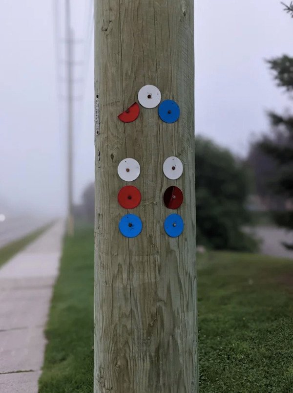 What are these metal markers on a utility pole that don’t have any embossed identification tags or serial numbers?

A: I suspect the little bar code tag to the left is the pole identifier. The different colored tags likely indicate the phase (A,B or C) of the conductors. Note that the tags are arranged in the same orientation as the conductors, three at the top and three vertical on either side.