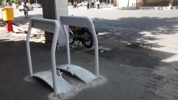 Seen often in Tehran, Iran, and nowhere else in the world. On the sidewalks, made of metal, maybe 4 feet tall.

A: From what found it’s used for wheelchairs to go over un level ground. Looks like there is a dip there.