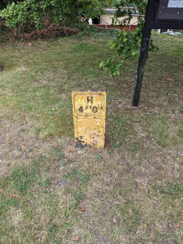 metal signs stuck in the ground all over England that have feet and inches stamped into them

A: They’re fire hydrant markers.