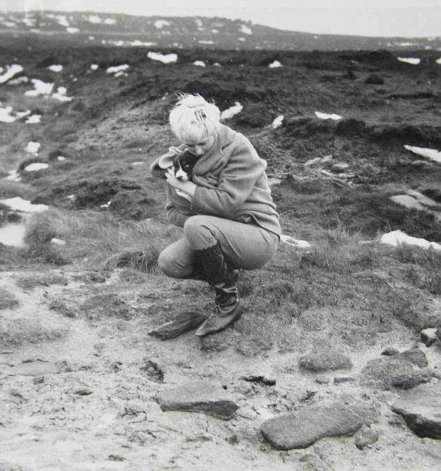 Myra Hindley, crouches looking at the ground. Detectives would learn that her and her partner Ian Brady took these pictures on shallow graves of the children they had tortured and murdered