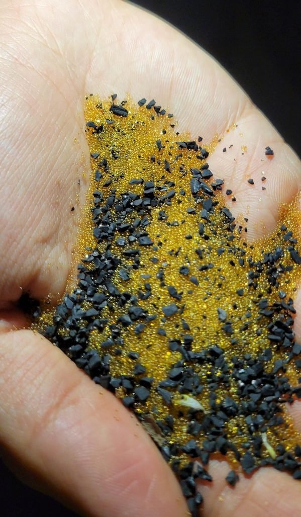 What are this yellow transparent little pebbles that I found at a hill, it was mixed with little pieces of rubber, it has no odor, and they feel solid to the touch (like plastic)

A: The yellow looks like used deionization resin, as said used for water treatment. So the black may be carbon…which also is used for water treatment.