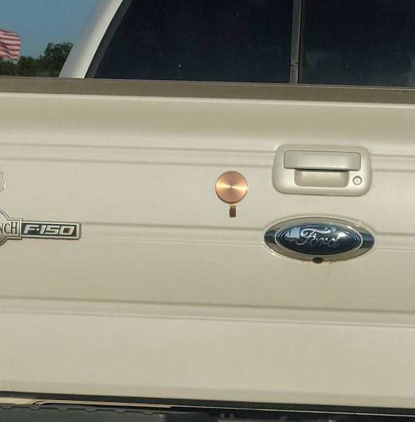 This copper circle on the tailgate of a truck. Looks like a tag of some kind hanging out of it. A few inches across. Found in Texas. What is this thing?

A: Magnetic wreath hanger