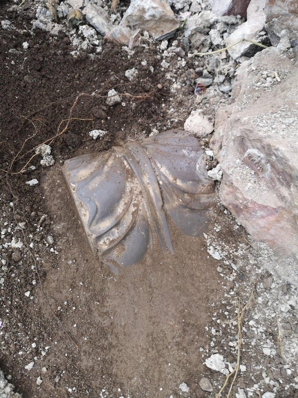 Found under a wall in Wales, UK – solid metal with bolts in the concrete around it

A: It could be a base plate or fixing for an old iron railing