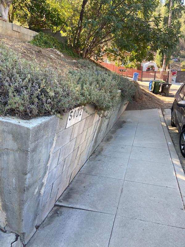 This failing retaining wall won’t last much longer. Some movement over the years has taken place and has caused the wall to lean into the sidewalk.