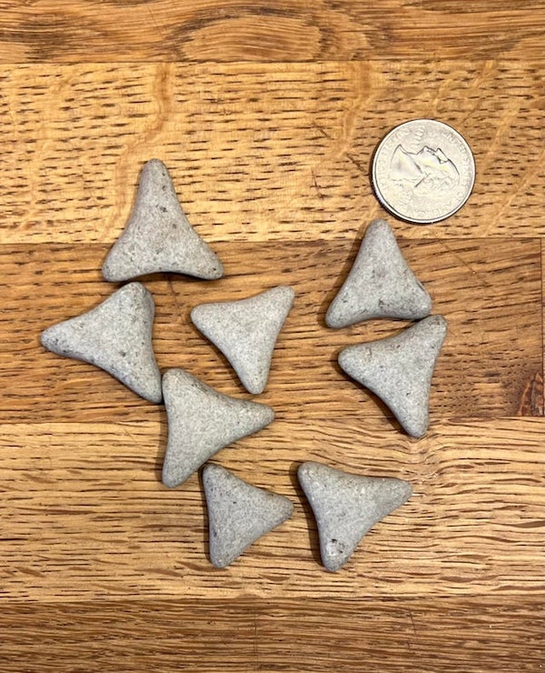 Small hard triangular objects found in gravel road.

A: They are ceramic tumbling media.