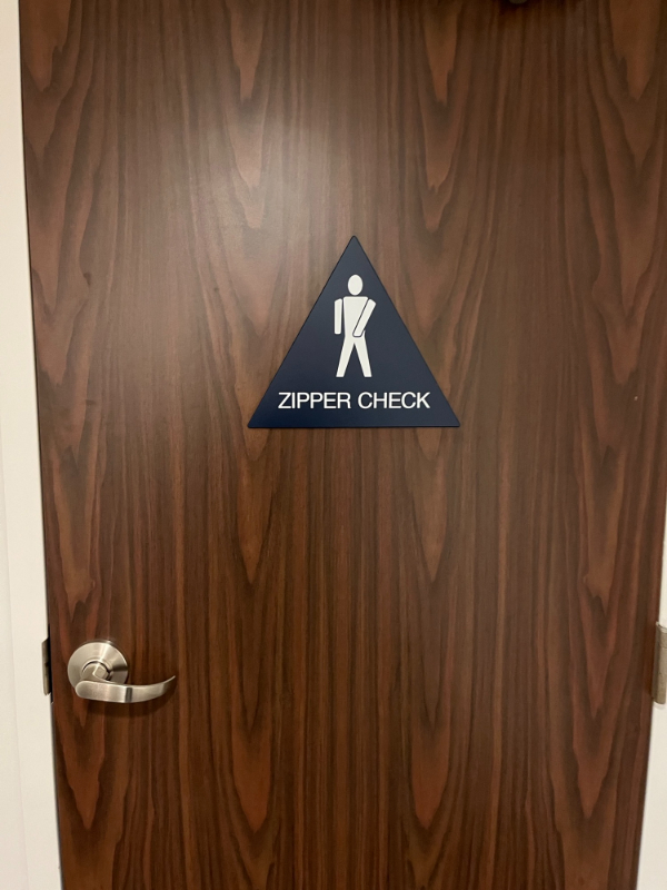 “This zipper check sign on the backside of the door of a hotel’s lobby bathroom.”