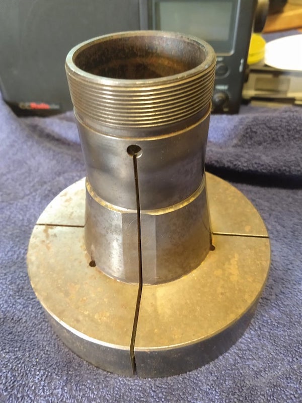 This is machined from one piece of steel. The cuts go all the way through so that it rings like a tuning fork. It is 6 inches tall and 6 inches in diameter. It looks like something a machinist would use with a lathe, but it wasn’t found with anything that gives a clue.

A: This is a workholding collet, generally used in a lathe but can also be used on a milling machine with an appropriate collet holding system. This collet looks like it was machined from an emergency collet to hold a specific part.