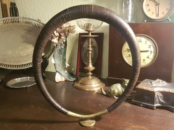 25cm high, the stand might be bronze, the ring is made of many separate wooden pieces, what could it be?

A: It resembles a tribal necklace from Indonesia that’s made from coconut palm.