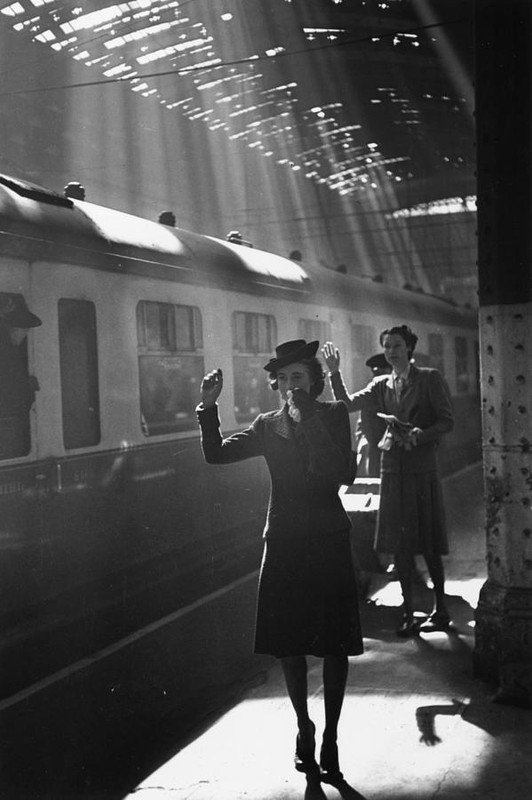 Tearful wives waving goodbye as a troop train pulls out of a station, 1942