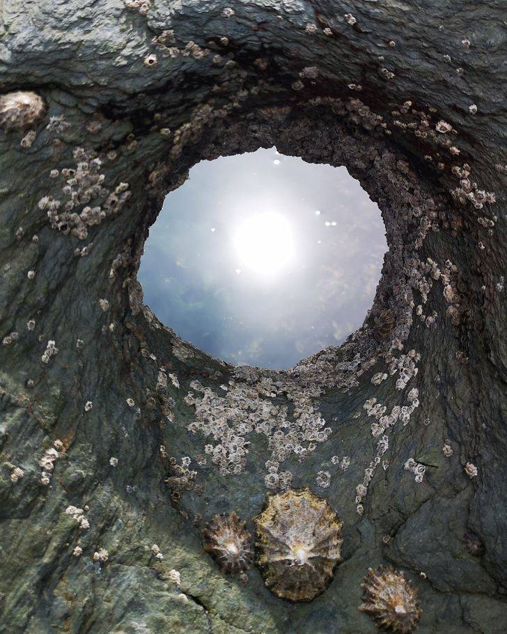 “This hole in a rock makes it look like a tunnel looking up at the sky and sun. It’s actually a reflection of water on the other side.”
