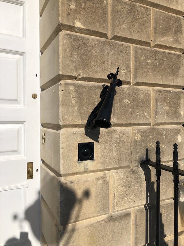 What is this conical metal thing next to the door? Found in southern England

A: It’s a large scale candle snuffer