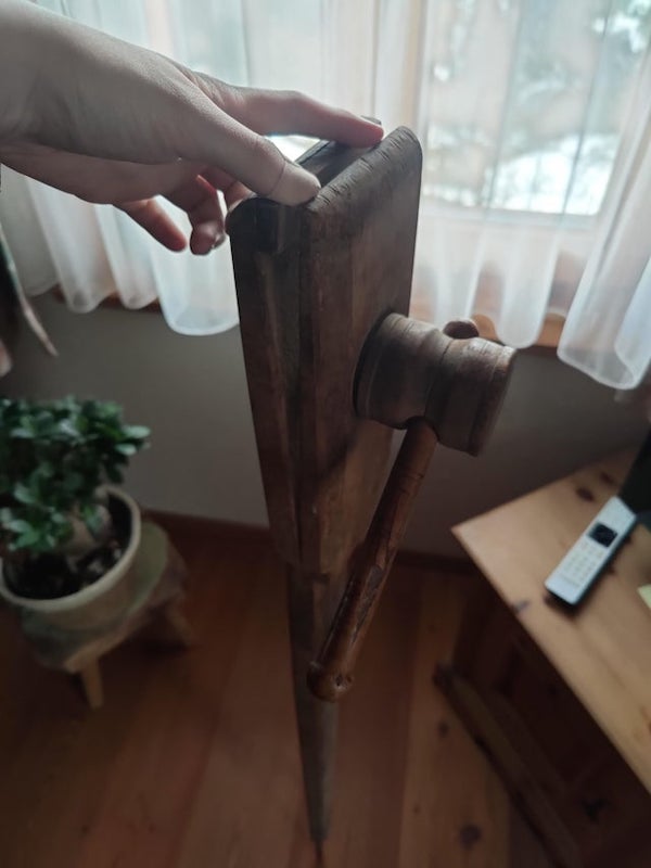 Found in our basement, completely wooden except for a metal tip at the bottom of it. My grandparents were farmers / carpenters. The top wrench can be tightened completely

A: That looks like a sewing pony. You put two leather pieces together and it provides a solid and stable hand for an even saddle stitch.