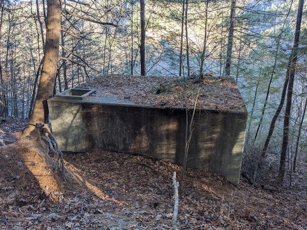 Found in Natural Bridge State Resort Park, KY off a trail. But I’ve also seen them in Cherokee near NC and TN borders also on trails. Seemingly empty inside, no door on this one, but seen elsewhere with a door. Used to have a lid with vent pipe on top entrance. Maybe 7’x35’x21′ if I had to guess.

A: “About 2.25-miles from the Natural Bridge on the Hood’s Branch Trail, the trail passes through a swampy section that was once cleared for a small farm. Cross two small footbridges and you’ll soon see a trail shelter built by the Civilian Conservation Corps when they maintained a camp at Natural Bridge in the 1930’s.”
