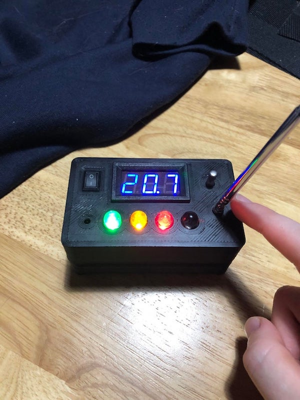 Small black box with four LEDs, an aerial and some sort of terminal.

A: After some short and uninteresting research, these contain theremin circuits which are conveniently set off by handheld 2 way radios. The inventor used a toy kit in the original. At least the “ghosts” can mimic vintage horror movie sounds as they haunt you
