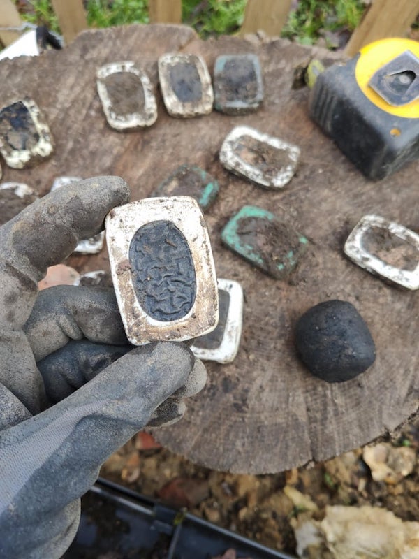 Found lots of these little things buried in the ground whilst digging out foundations for an extension in the UK. The white around the edge is some kind of plastic and the inside seems like charcoal, but could be something else. Anyone have any idea what they are?

A: They look like individual cells from a battery.