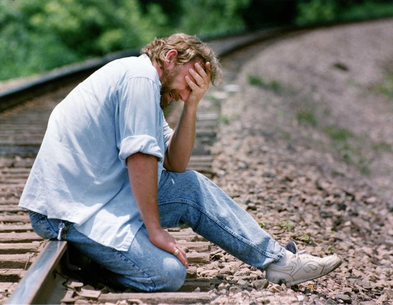 Randy Ertman sits on the railroad tracks near the location where the body of his daughter was found