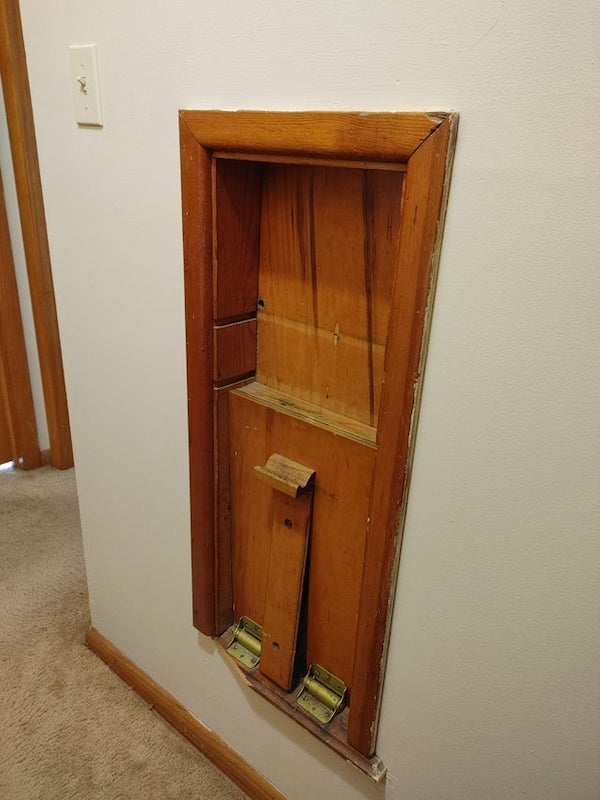 This built in wooden shelf/storage thing in our new house.

A: Fold down is for a seat. As this would have been the only phone, and was likely in the hallway, a chair would have been in the way. Would have been two shelves in the slot that stuck out beyond the face. Phone book in between, phone on top shelf. The hole just above the top shelf on left side is where the cord would have come through the wall.