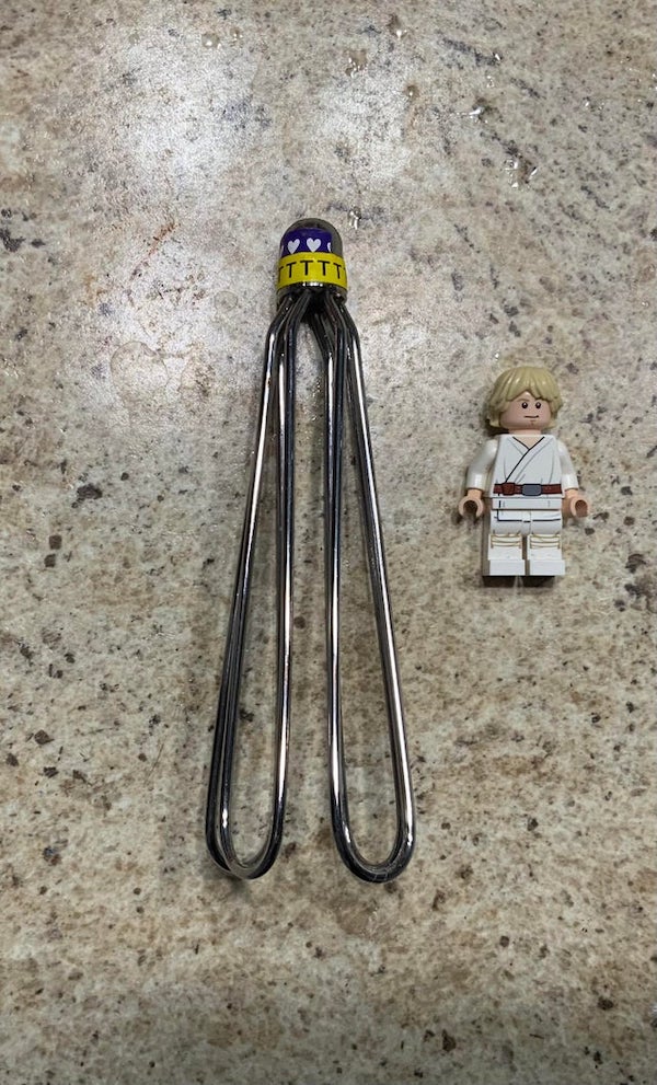 What is this metal object with Ts and hearts at the top? (Minifigure for scale)

A: It’s a bandage/gauze applicator for fingers or thumbs!