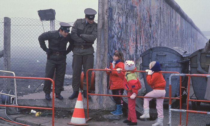 fascinating photos from history - West German School Children Pause To Talk With Two East German Border Guards Beside An Opening In The Berlin Wall During The Collapse Of Communism In East Germany In November 1989.